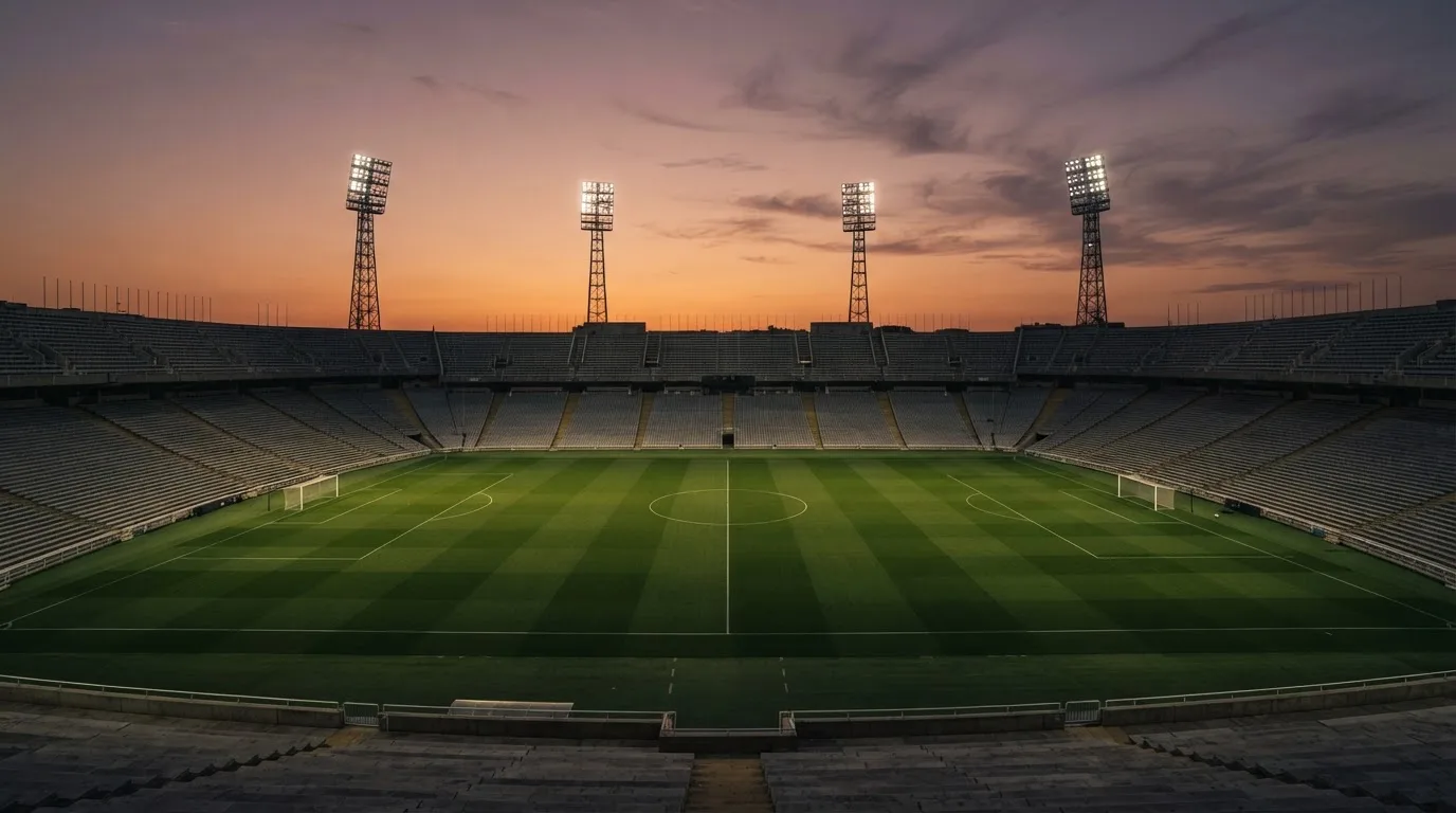 Un estadio de fútbol vacío con torres de iluminación al atardecer