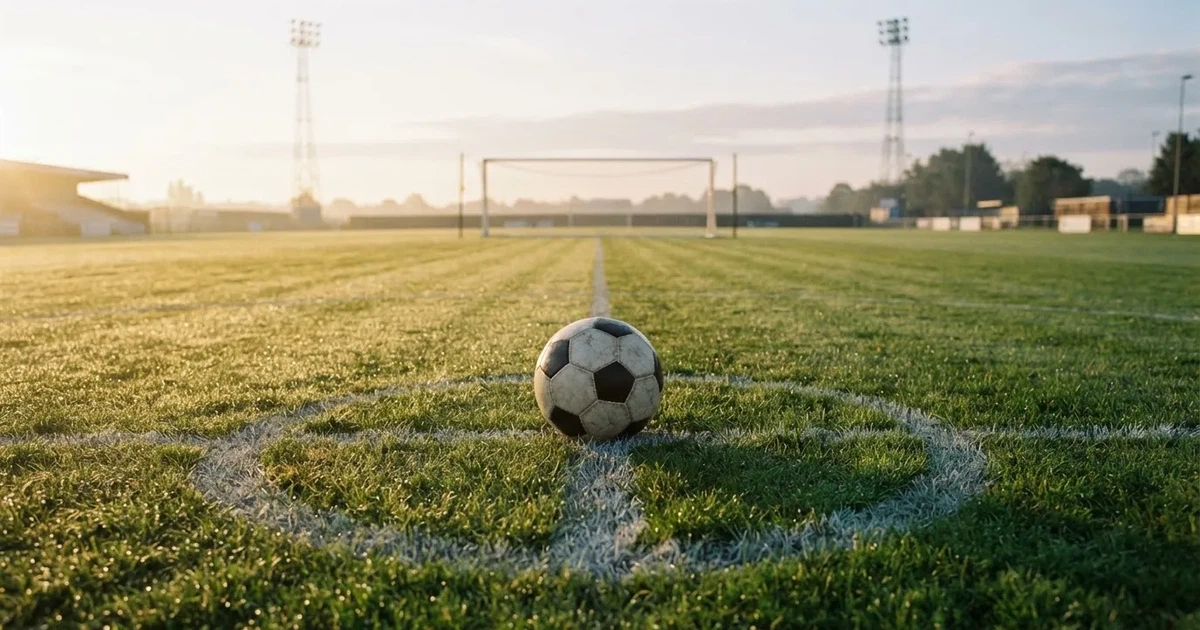 Un balón en el punto central de un campo de césped a la luz de la mañana