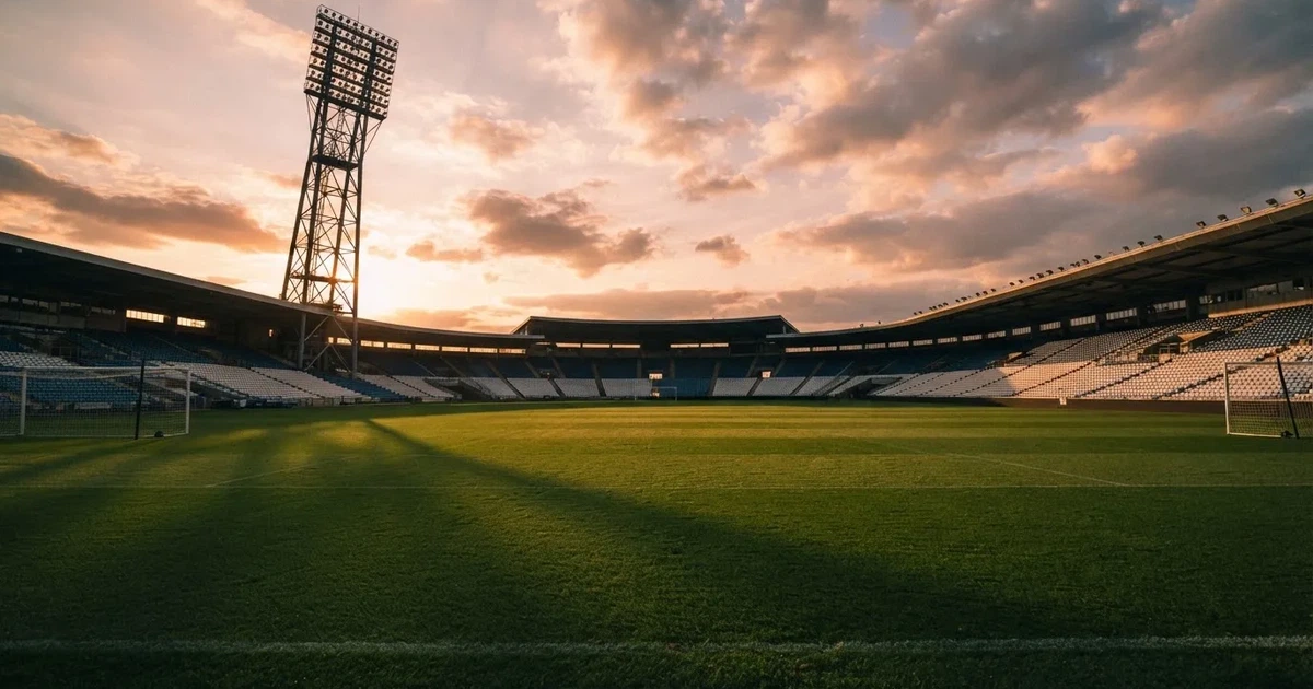 Un estadio de fútbol vacío con torres de iluminación al atardecer