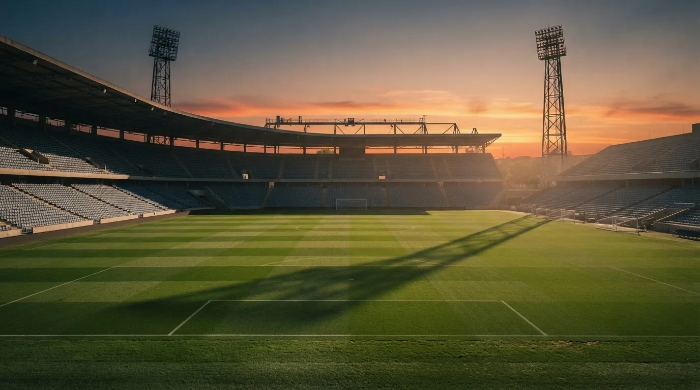 Un estadio de fútbol vacío con torres de iluminación al atardecer