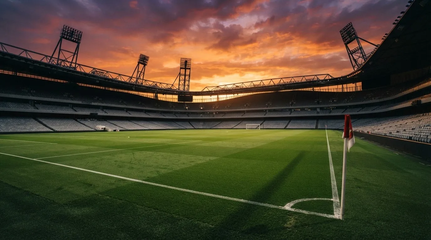 Un estadio de fútbol vacío con torres de iluminación al atardecer