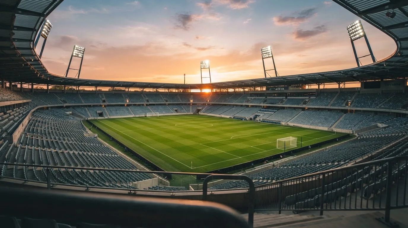 Un estadio de fútbol vacío con torres de iluminación al atardecer