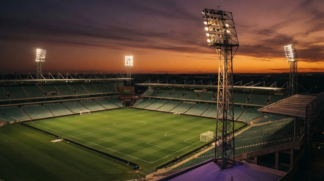 Un estadio de fútbol vacío con torres de iluminación al atardecer
