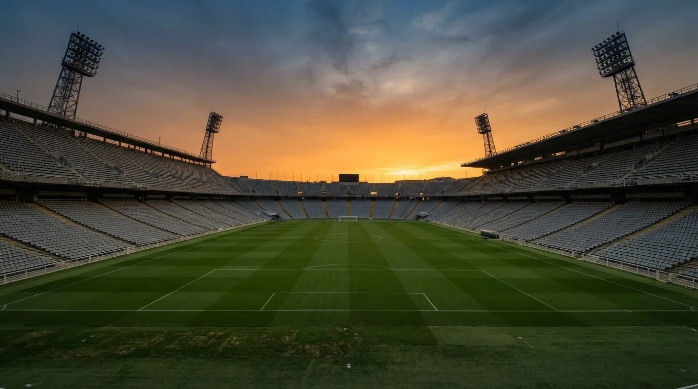 Un estadio de fútbol vacío con torres de iluminación al atardecer
