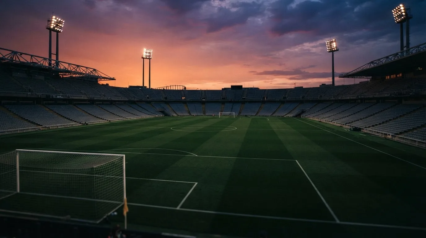 Un estadio de fútbol vacío con torres de iluminación al atardecer