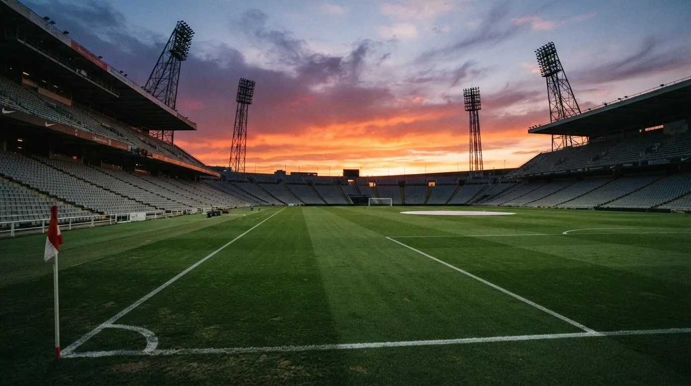 Un estadio de fútbol vacío con torres de iluminación al atardecer