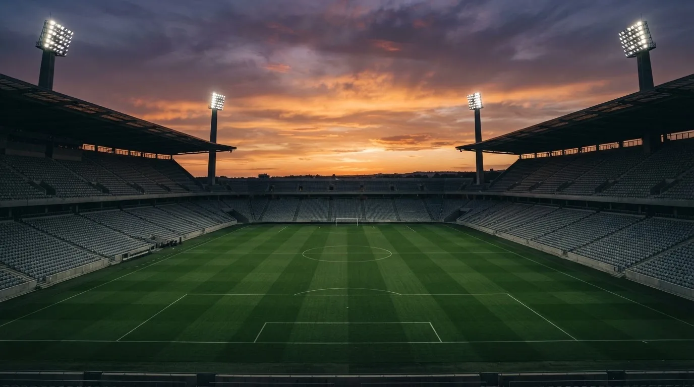 Un estadio de fútbol vacío con torres de iluminación al atardecer