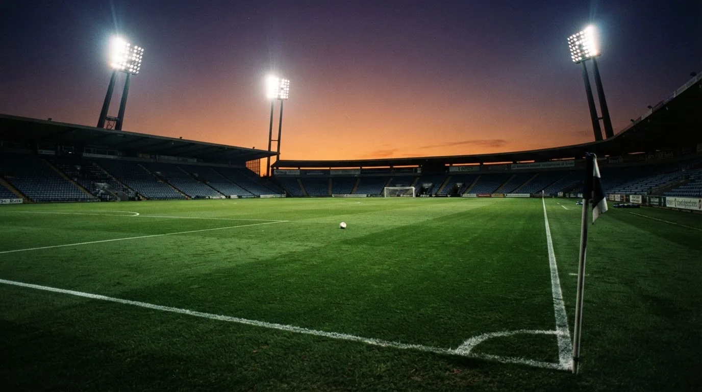Un estadio de fútbol vacío con torres de iluminación al atardecer