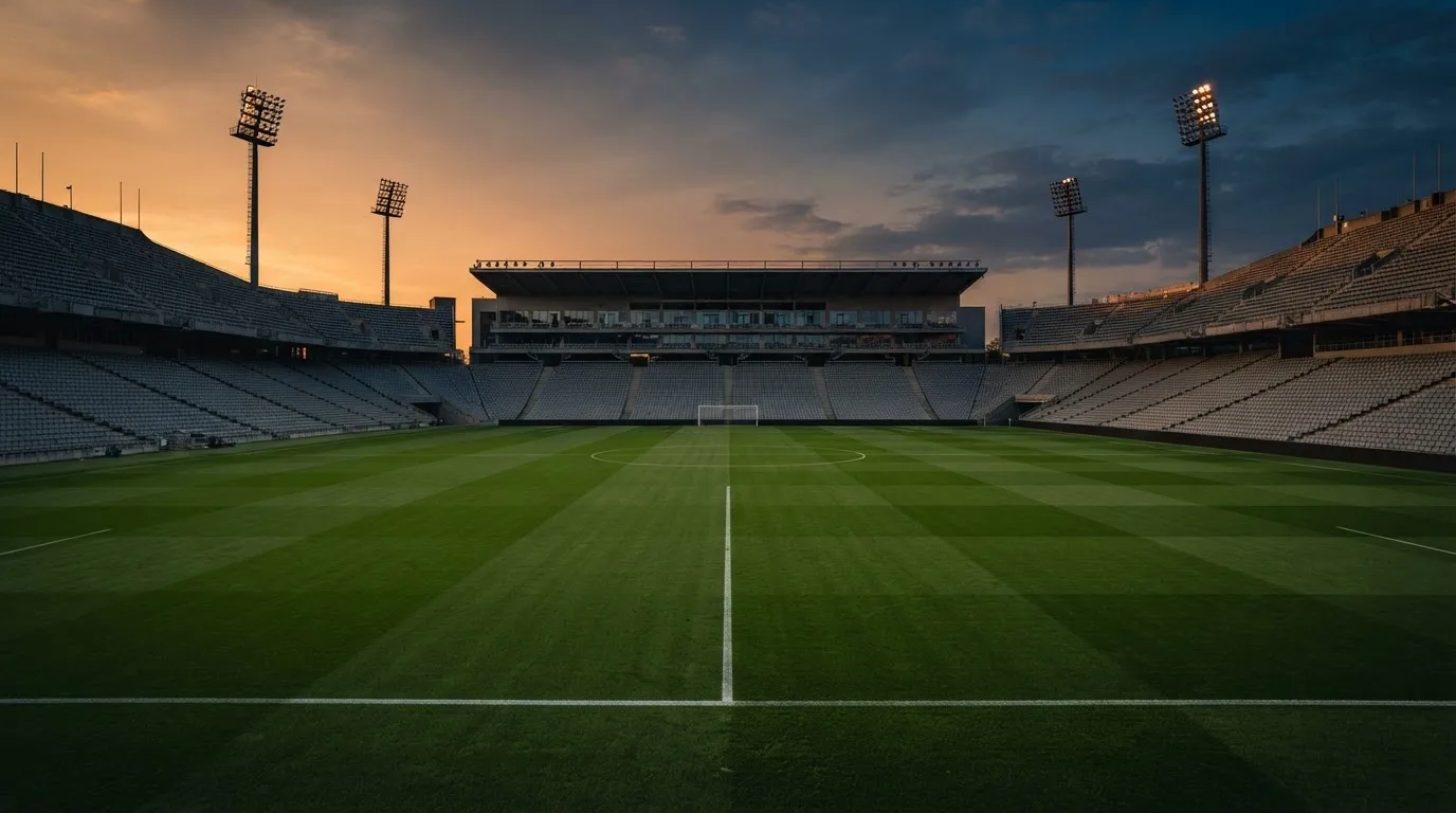 Un estadio de fútbol vacío con torres de iluminación al atardecer