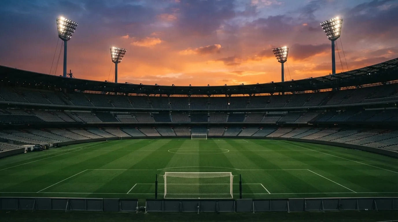Un estadio de fútbol vacío con torres de iluminación al atardecer