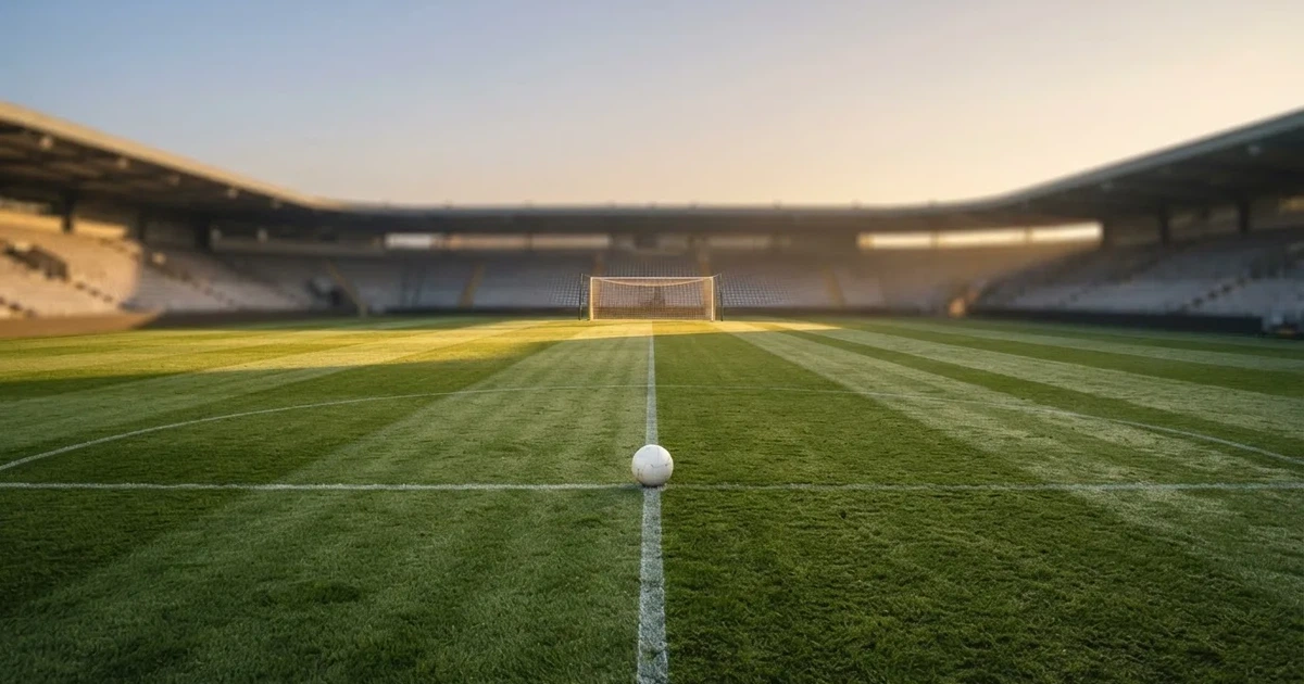 Un balón en el punto central de un campo de césped a la luz de la mañana