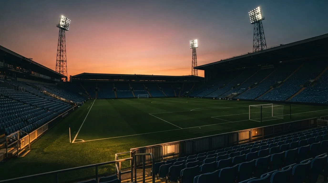 Un estadio de fútbol vacío con torres de iluminación al atardecer
