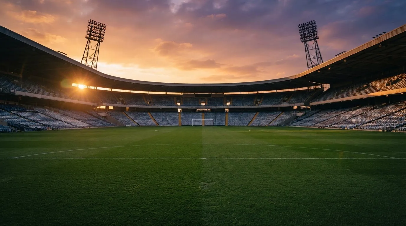 Un estadio de fútbol vacío con torres de iluminación al atardecer